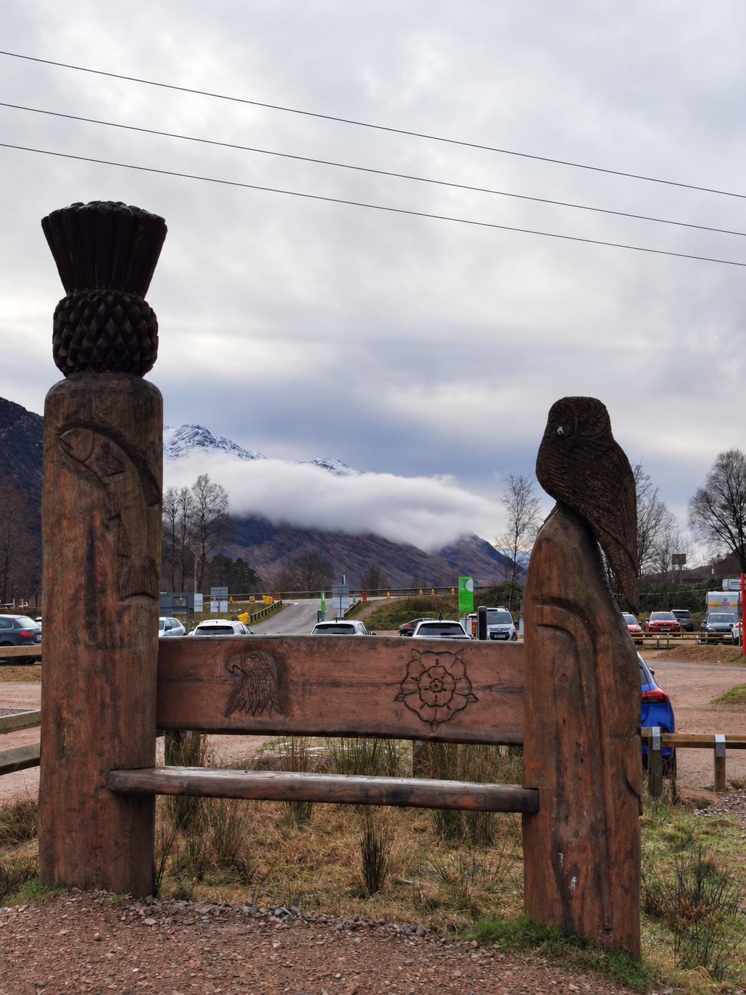 Wooden carvings with misty Highland mountains beyond.